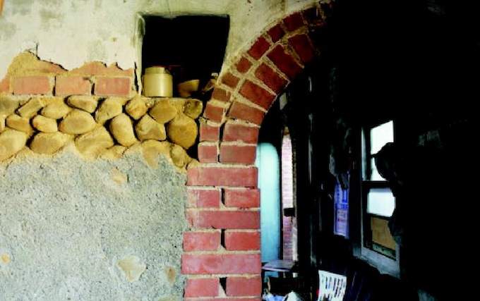 屋內斑駁的牆，可看見建築材料：磚頭、石頭、石灰拌砂土。水泥部分是天虎叔自己砌抹上的。